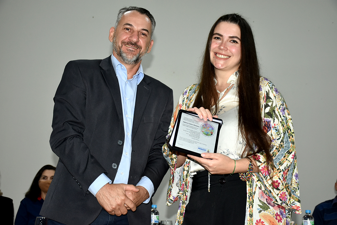 Prefeito Mauricio Soligo entrega uma placa em homenagem à Patrona Débora Mattana